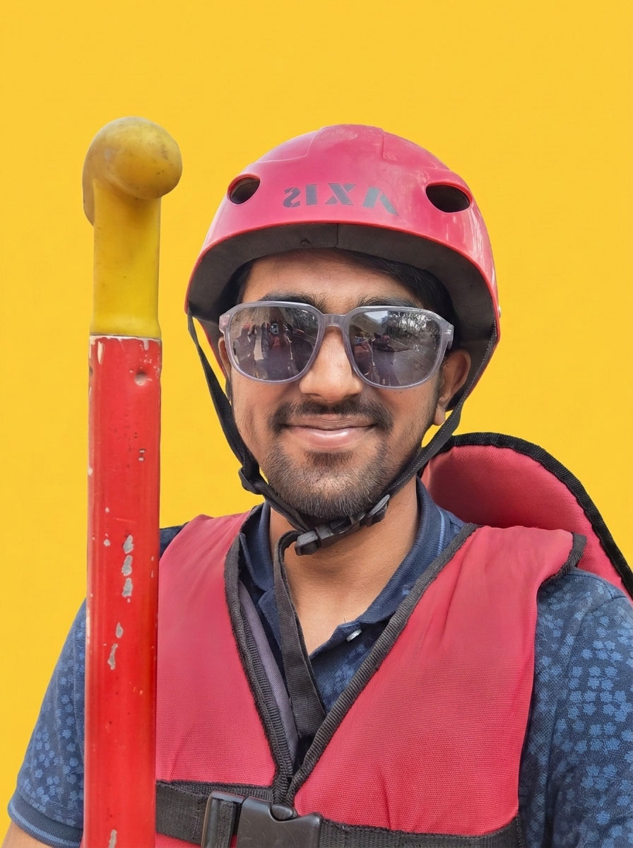 Man in a helmet and life vest, smiling for the camera.